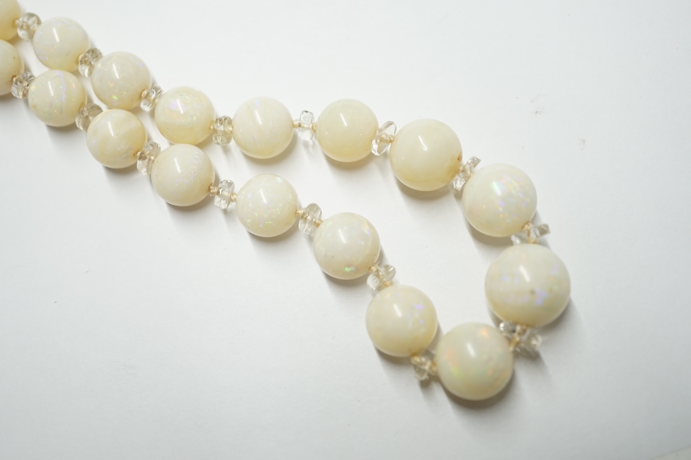 A single strand graduated white opal circular bead necklace, with paste? spacers and white metal clasp, 58cm. Condition - fair